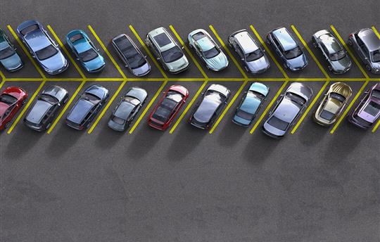 aerial view of a parking lot lane, each spot filled with a different car
