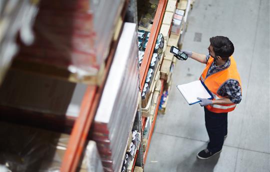 Licensed Worker with scanner making review of goods in warehouse