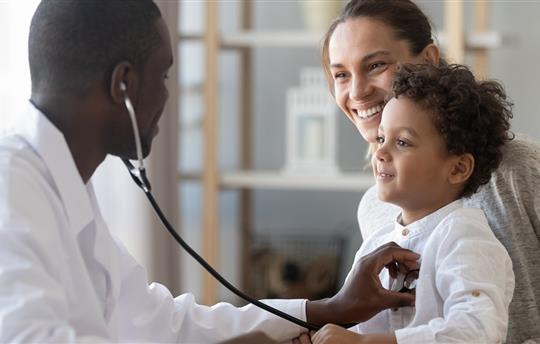 pediatrician holds stethoscope to exam child patient