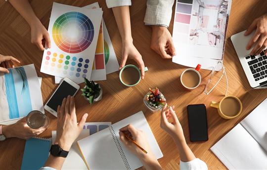 Team of professional designers working together at table, top view