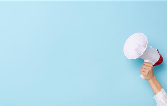 hand holding megaphone over light blue background