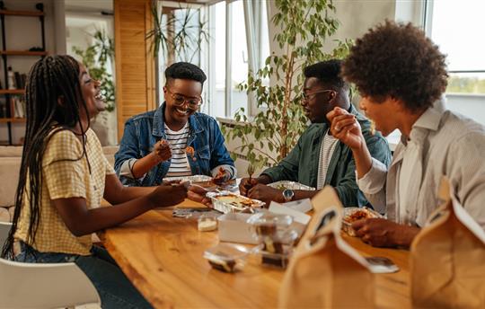 Group of young adults eating take out food at home