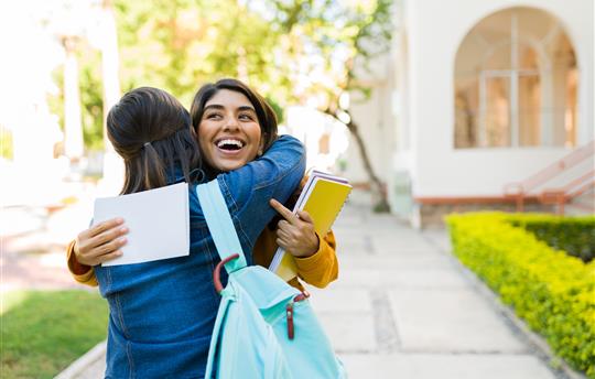 happy woman celebrates being accepted into college hugging mother