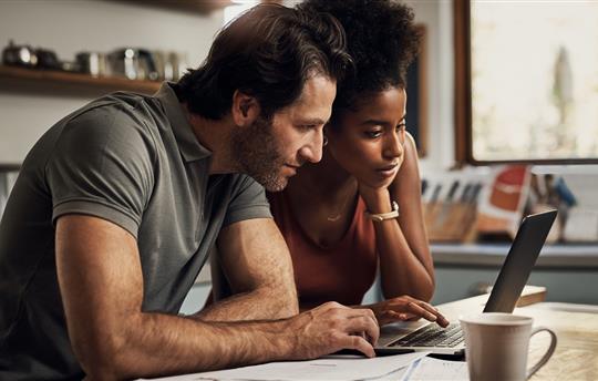 Couple with a laptop doing finance paper work together at home.