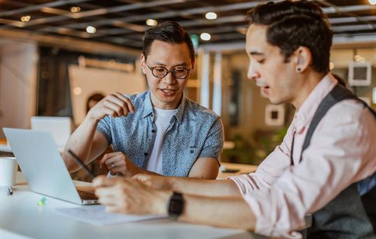 Two businessmen discussing over a document at modern coworking space