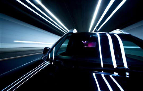 close-up of black car in motion inside lit tunnel