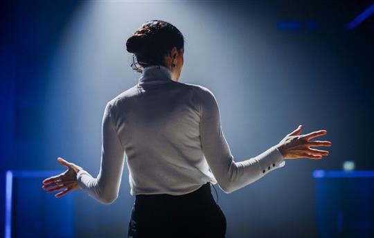 Woman speaking on stage facing audience