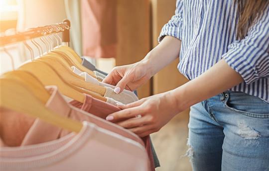 female shopper looking through tops hanging on a clothing rack