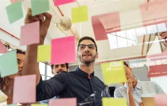 a group of businesspeople brainstorming with notes on glass wall in an office