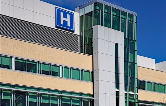 exterior view of a hospital with blue H hospital sign