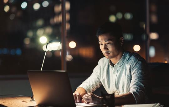 man working on his laptop in the evening