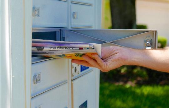 hand pulling stack of mail out of mailbox