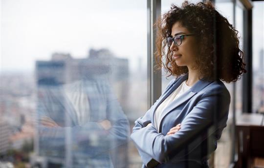female businesswoman with arms crossed looking out office window