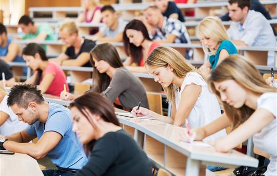 college students in a lecture hall taking notes