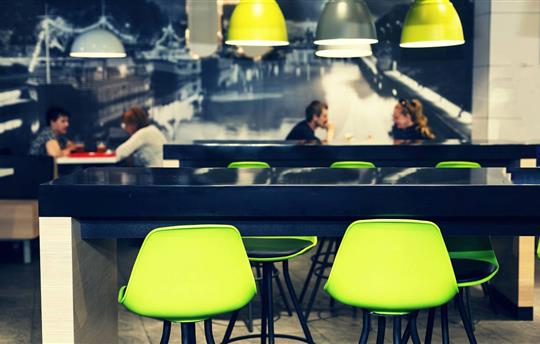 Interior of a modern fast food restaurant with bright green chairs