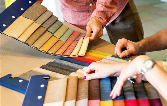 three sets of hands going through upholstery swatches