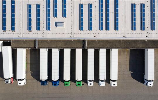 Aerial view of large semi trucks parked along warehouse-distribution center