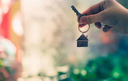 hand holding key with a house keychain
