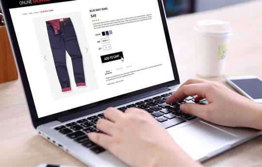 buying blue navy jeans on ecommerce website with smart phone, credit card and coffee on wooden desk