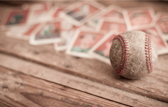 worn baseball on wooden bench with baseball cards blurred in the background