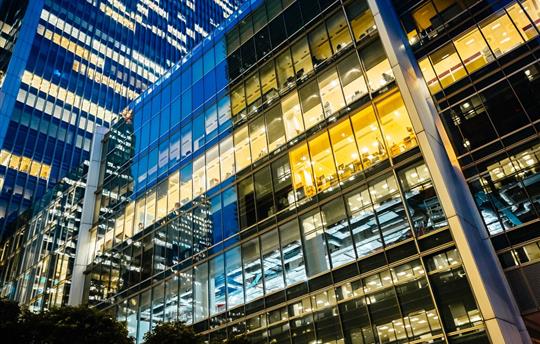 side of office building at night with office lights on