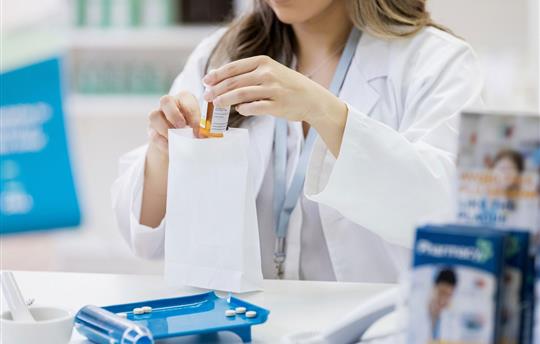 female pharmacist placing medication in a white paper bag