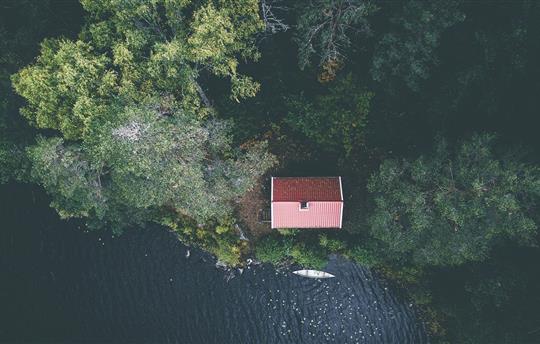 Aerial view of a cabin in the woods near the edge of a lake