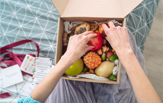 hands reaching into a box of fruit