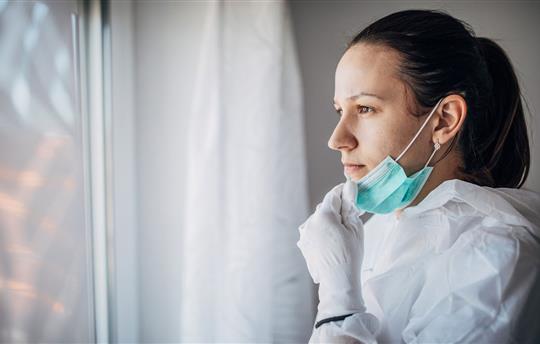 One woman, worried female doctor in protective suit, looking through the hospital window.