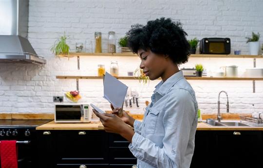 female looking through a stack of mail in her kitchen