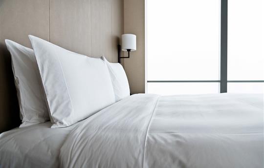 clean hotel bed with two white pillows and white sheets