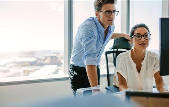Corporate professionals looking at computer monitor in office