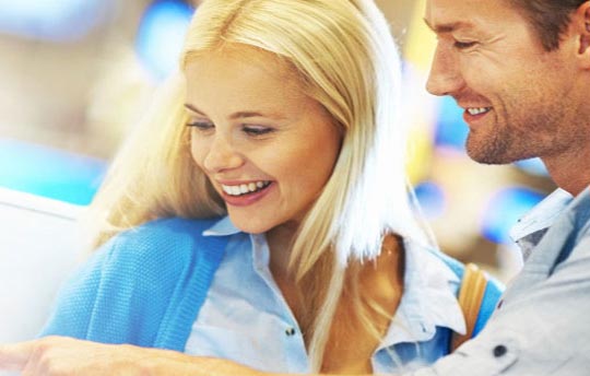 male and female smiling together as they look at a piece of paper