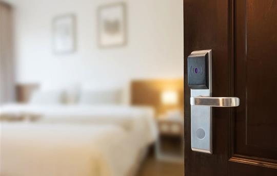door with hotel room card reader opening to show inside hotel room