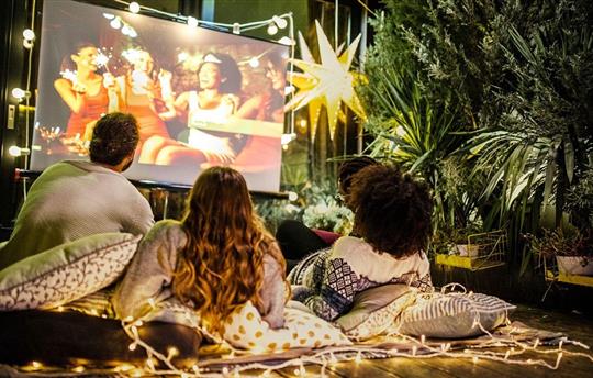 family watching movie on large screen outdoors