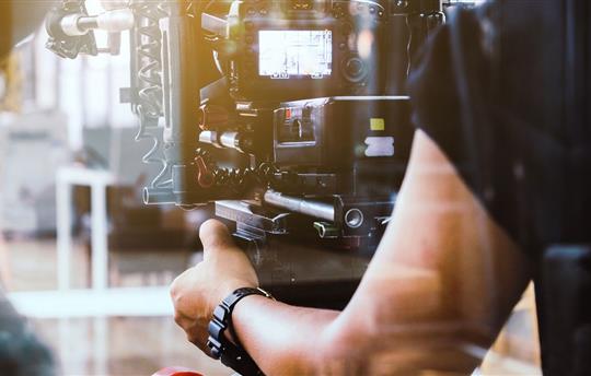 Videographer positioning video camera at subject