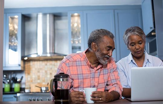 Senior couple drinking coffee and looking at laptop
