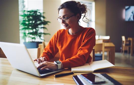 Professional young copywriter in trendy eyewear working on creation advertising content typing on laptop computer