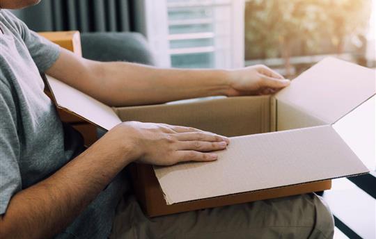 man sitting on a couch and opening a package on his lap