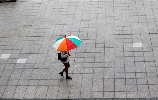 Person walking outside holding colorful umbrella