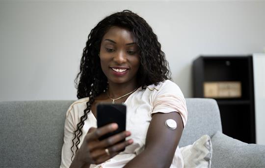 woman using glucose monitor at home