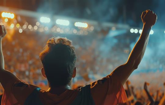 excited fan with arms raised at a basketball game