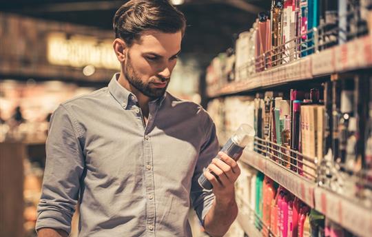 bearded man in button-down shirt holding a product in the grooming aisle