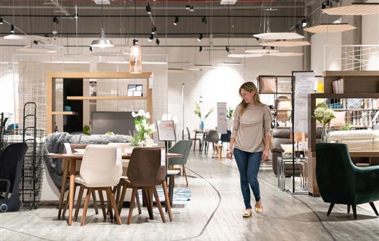 smiling female shopper at a furniture store looking at a table and chairs