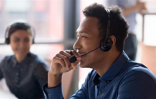 Smiling young call center agent laughing at workplace